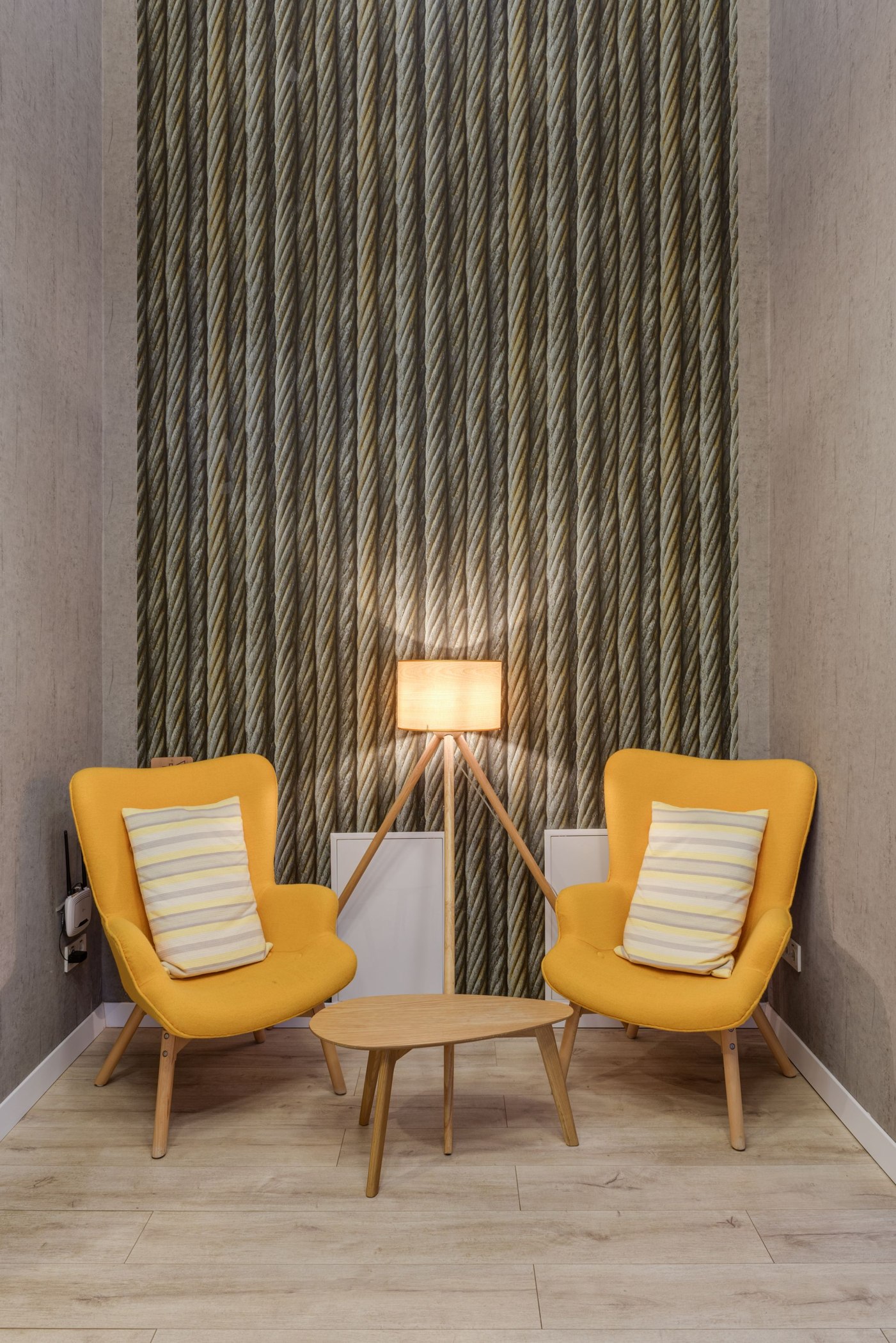 Seating area with yellow chairs and tall rope-patterned wallpaper feature wall